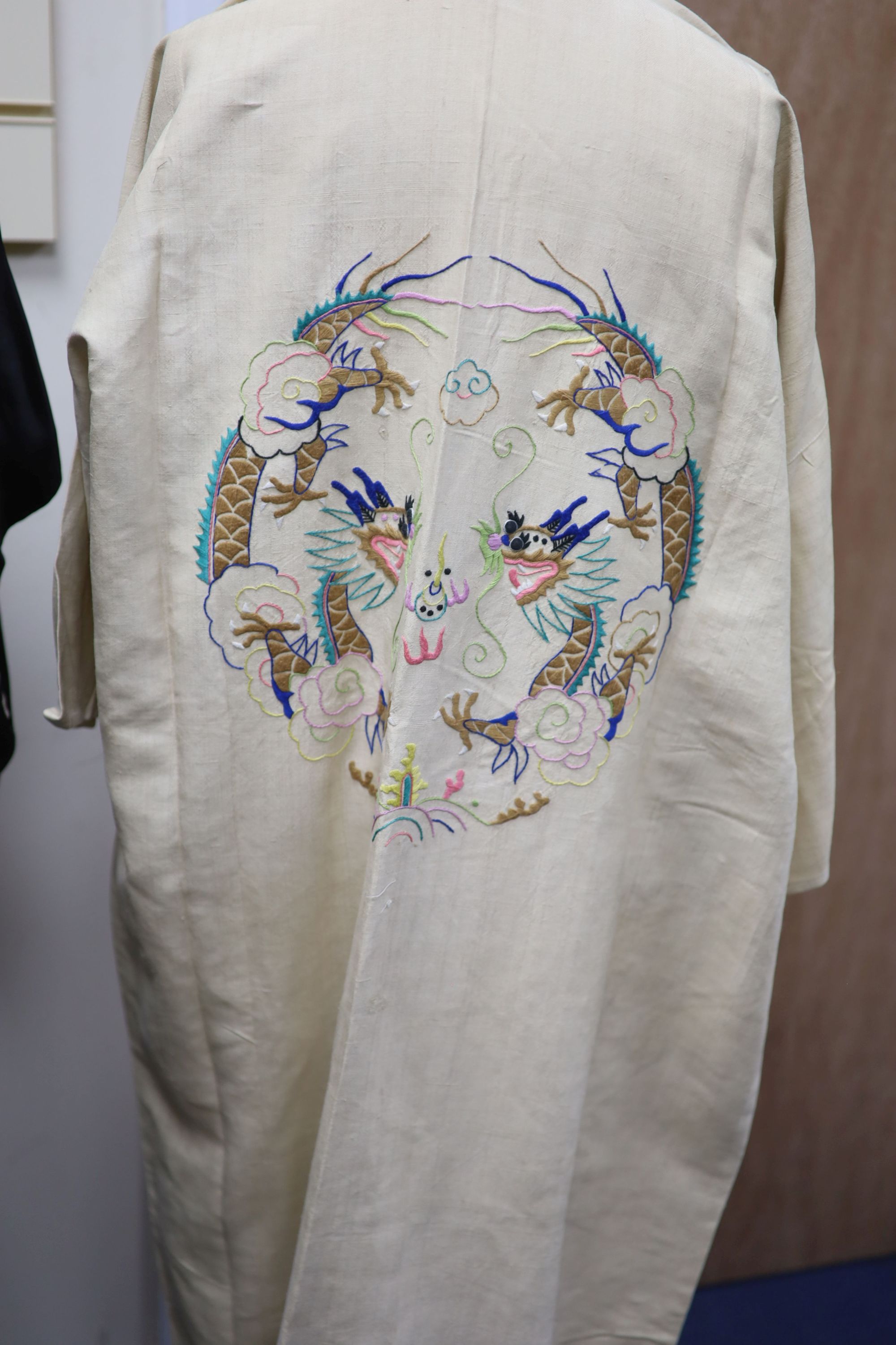 A Japanese black silk satin kimono embroidered with a white silk dragon, 133cm long and a cream silk multi-coloured embroidered dragon